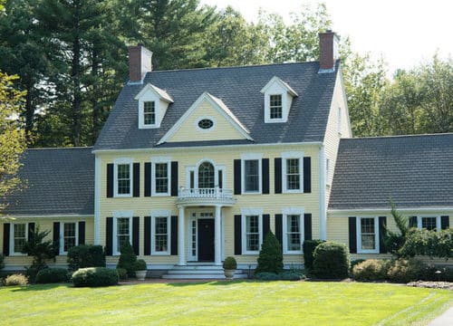classic home with soft yellow shade and black shutters
